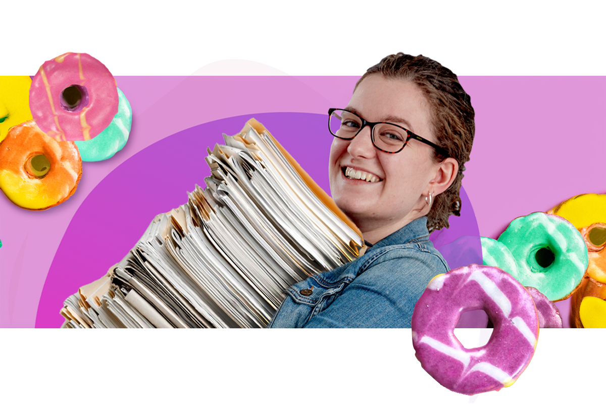 Hannah Edwards from HeyYou! Digital carrying a huge stack of papers and smiling at the camera. There are bright iced biscuits decorating the image.